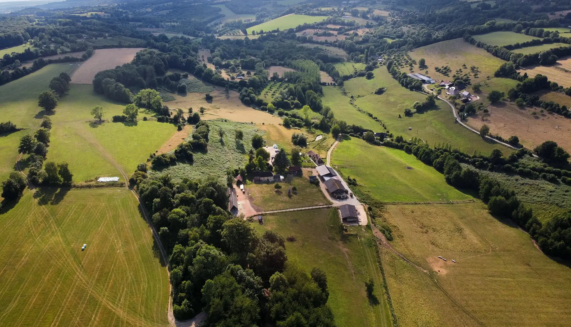 La ferme de la Foucaudière vue du ciel : ses prairies, ses haies bocagères et les collines du Pays d'Auge